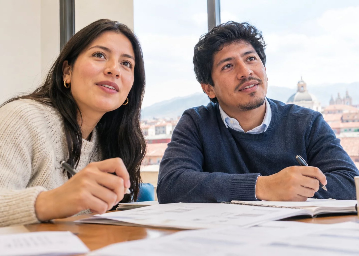 Mesa de seminario con apuntes repartidos y dos personas trabajando